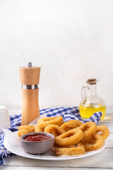 Golden onion rings with ketchup sauce, airfryer cooked tasty onion ring snacks on white wooden table copy space