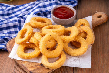 Golden onion rings with ketchup sauce, airfryer cooked tasty onion ring snacks on white wooden table copy space