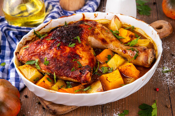 Roasted baked chicken quarter with pumpkin and potato stew, garlic and aromatic herbs. Tasty autumn comfort food, ideas for Thanksgiving family dinner