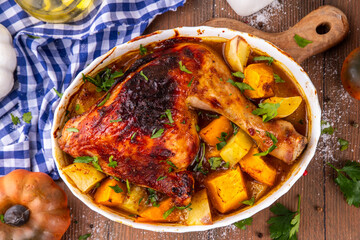 Roasted baked chicken quarter with pumpkin and potato stew, garlic and aromatic herbs. Tasty autumn comfort food, ideas for Thanksgiving family dinner