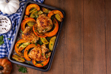 Roasted baked chicken thigh with pumpkin and potato wedges, garlic and aromatic herbs. Tasty autumn...