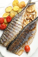 Tasty roasted mackerels with lemon, tomatoes and potatoes on table, top view. Homemade seafood dish