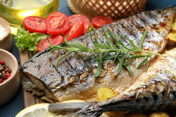 Tasty roasted mackerels served with spices and vegetables on table, closeup. Homemade seafood dish