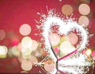 Heart-shaped sparkler against bokeh background