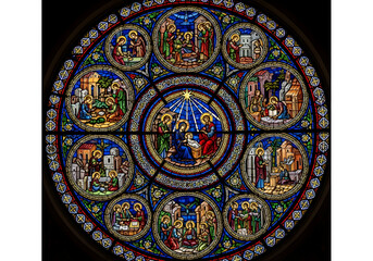 A vibrant circular stained glass window depicting scenes from the nativity story, featuring intricate details and a rich array of colors.