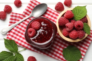 Tasty jam, fresh ripe raspberries and leaves on white wooden table, flat lay.