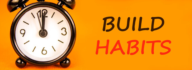 Build habits symbol. Concept word Build habits on beautiful orange paper. Beautiful black alarm...