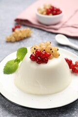 Tasty panna cotta with currants and mint on light grey table, closeup