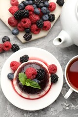 Tasty panna cotta with berries and jam on light grey table, flat lay