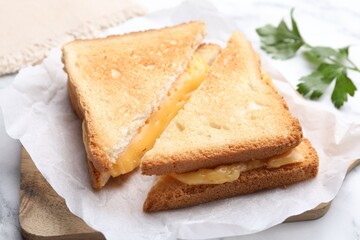 Tasty sandwiches with melted cheese and parsley on table, closeup