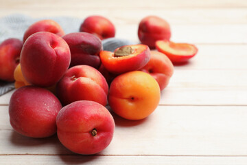 Fresh ripe apricots on light wooden table, closeup. Space for text