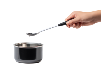 A hand holds a spoon above a small saucepan