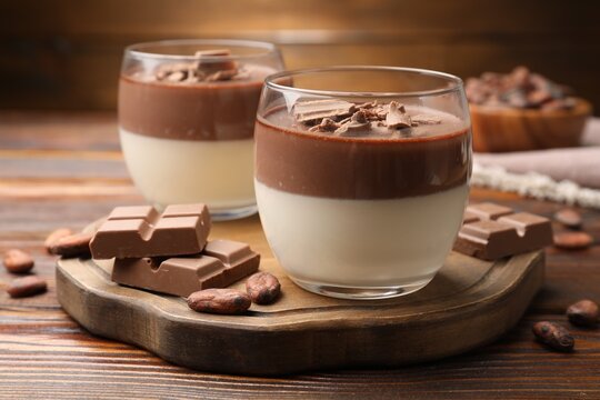 Delicious panna cotta with chocolate and cocoa beans on wooden table, closeup