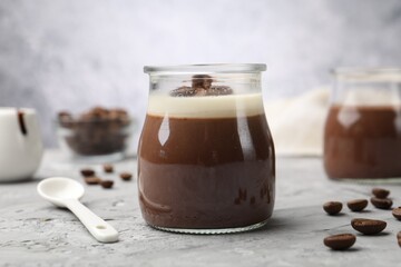 Delicious panna cotta and coffee beans on grey textured table, closeup