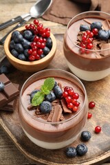 Delicious panna cotta with chocolate, berries and mint on table, closeup