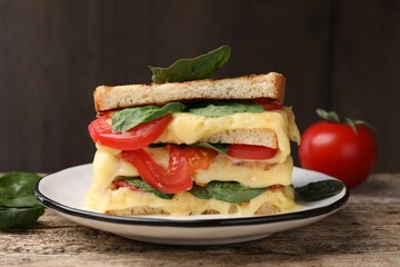 Delicious sandwiches with melted cheese, spinach and tomatoes on wooden table, closeup