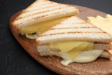 Tasty sandwiches with melted cheese on gray textured table, closeup