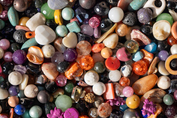 Colorful strings of gemstone beads displayed for sale, vibrant mix of textures and tones in jewelry craft market.
