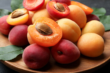Many fresh apricots and green leaves on table, closeup