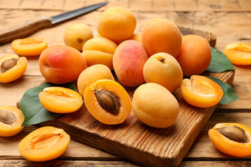 Many fresh apricots and green leaves on wooden table, closeup