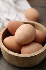 Raw chicken eggs in bowl on wooden table, closeup