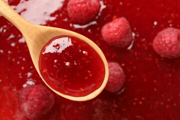 Delicious raspberry jam with fresh berries and spoon as background, top view