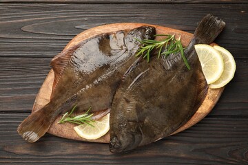 Fresh flounder fish, lemon and rosemary on wooden table, top view. Raw seafood