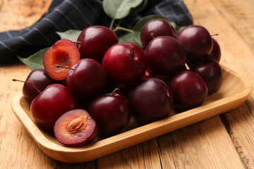 Whole and cut cherry plums on wooden table, closeup