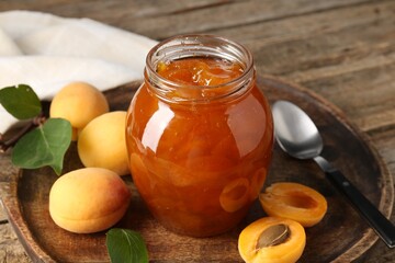 Tasty apricot jam and fresh fruits on wooden table, closeup