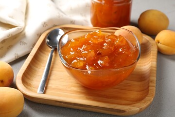 Tasty apricot jam and fresh fruits on light grey table, closeup