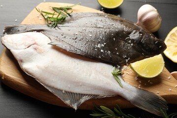 Fresh raw flounder fish and spices on black wooden table, closeup. Seafood