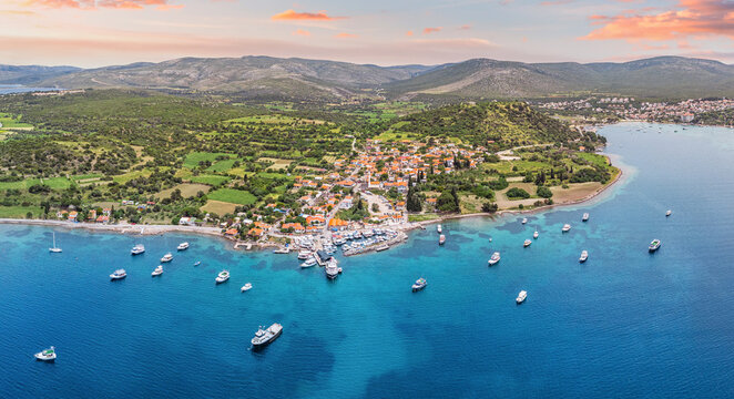 Aerial view of boats anchoring near the coast of a picturesque coastal village surrounded by lush green hills and crystal clear turquoise waters