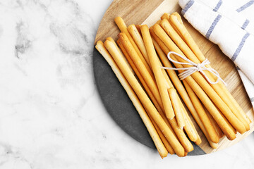 Delicious grissini sticks and napkin on light marble table, top view. Space for text