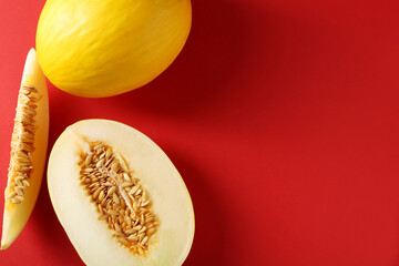 Whole and cut ripe melons on red background, flat lay. Space for text