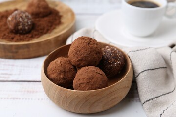 Delicious homemade candies with cocoa powder and coffee on white wooden table, closeup