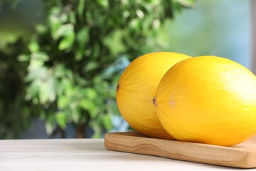 Whole ripe melons on white wooden table, closeup. Space for text