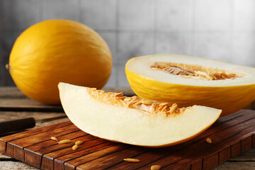 Cut and whole ripe melons on wooden table, closeup