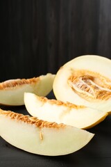 Cut ripe melon on black wooden table, closeup