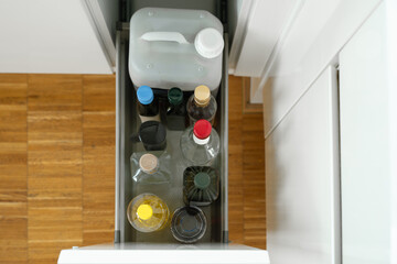 top view of a kitchen drawer showcasing an organized collection of various bottles including oils,...