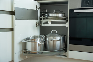 spacious kitchen cabinet showcasing neatly arranged stainless steel cookware including pots and lids on a rotating shelf for optimal storage and accessibility