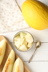 Cut and whole ripe melons on white wooden table, flat lay