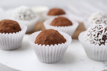Delicious homemade candies with cocoa powder and coconut flakes on table, closeup