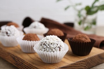 Delicious homemade candies with cocoa powder and coconut flakes on table, closeup
