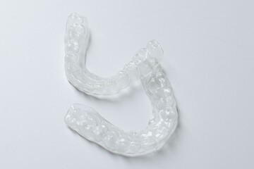 Clear aligners on light grey background, closeup