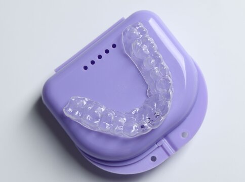 One clear aligner and retainer case on light grey background, top view