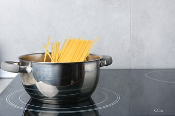 Fresh tagliatelle pasta boiling in pot on electric stove, space for text