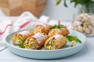 Delicious cannoli with cheese, nuts and mint on white table, closeup