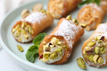 Delicious cannoli with cheese, nuts and mint on table, closeup