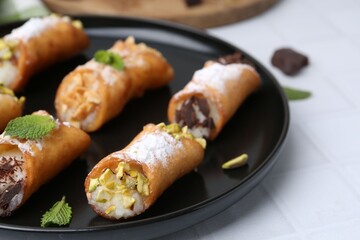 Delicious cannoli with cheese, nuts, powdered sugar, chocolate and mint on white table, closeup