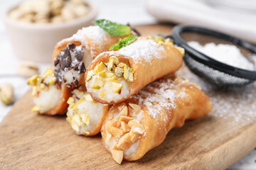 Delicious cannoli with cheese, nuts, powdered sugar, chocolate and mint on table, closeup